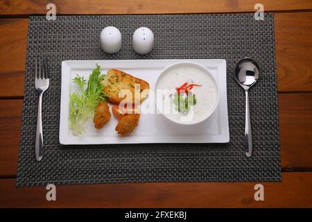 Creme der Pilzsuppe in einer weißen Schüssel mit angeordnet Geröstetes Brot und frischer grüner Gemüse-Salat als Beilage Auf einem weißen, grauen Servierbrett angeordnet Stockfoto