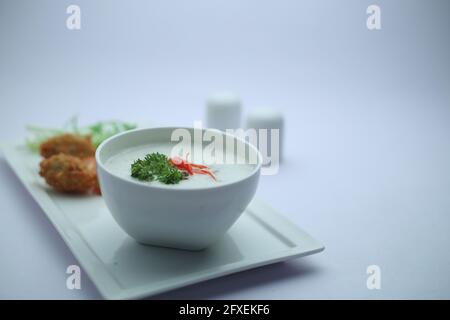 Creme der Pilzsuppe in einer weißen Schüssel mit angeordnet Geröstetes Brot und frischer grüner Gemüse-Salat als Beilage Auf einem weißen Servierbrett mit Weißwein angeordnet Stockfoto