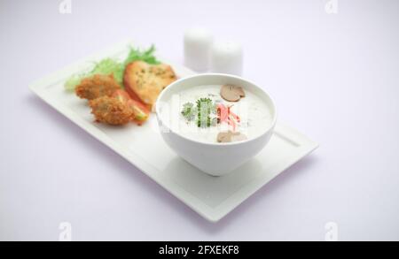 Creme der Pilzsuppe in einer weißen Schüssel mit angeordnet Geröstetes Brot und frischer grüner Gemüse-Salat als Beilage Auf einem weißen Servierbrett angeordnet Stockfoto