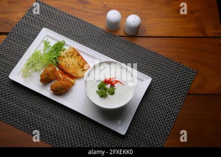 Creme der Pilzsuppe in einer weißen Schüssel mit angeordnet Geröstetes Brot und frischer grüner Gemüse-Salat als Beilage Auf einem weißen, grauen Servierbrett angeordnet Stockfoto