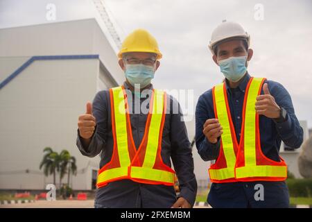 Zwei Ingenieur thump up Erfolg auf Baustellenhintergrund , zwei Menschen tragen medizinische Maske schützen covid19 Coronavirus , Arbeiter arbeiten Architekt Stockfoto