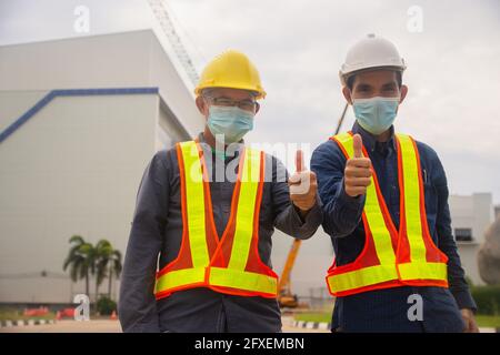 Zwei Ingenieur thump up Erfolg auf Baustellenhintergrund , zwei Menschen tragen medizinische Maske schützen covid19 Coronavirus , Arbeiter arbeiten Architekt Stockfoto