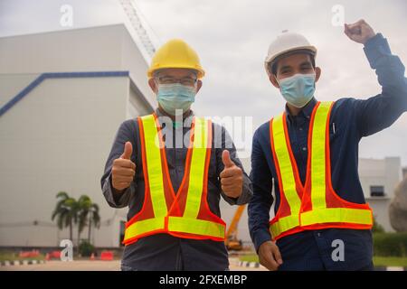 Zwei Ingenieur thump up Erfolg auf Baustellenhintergrund , zwei Menschen tragen medizinische Maske schützen covid19 Coronavirus , Arbeiter arbeiten Architekt Stockfoto