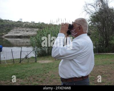 Del Rio, USA. Mai 2021. Joe Frank Martínez, Sheriff des Val Verde County im US-Bundesstaat Texas, blickt durch ein Fernglas auf die mexikanische Seite des Rio Grande. (To dpa: 'Bidens Problemzone') Quelle: Lena Klimkeit/dpa/Alamy Live News Stockfoto