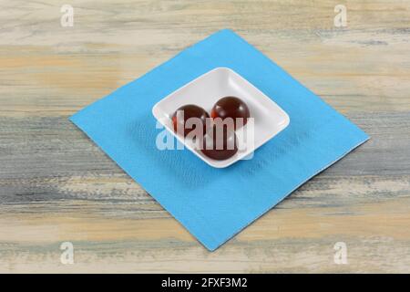 Thai Cola aromatisierte Gelee Gummy Süßigkeiten Stücke auf weißen Süßigkeiten Teller auf blauer Serviette auf dem Tisch Stockfoto