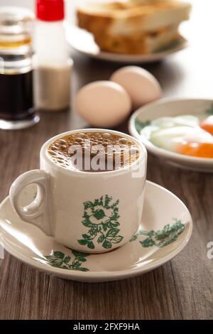 Gemeinsames orientalisches Frühstück in Malaysia, bestehend aus Kaffee, Nasi Lemak, Toastbrot und halbgekochtem Ei Stockfoto