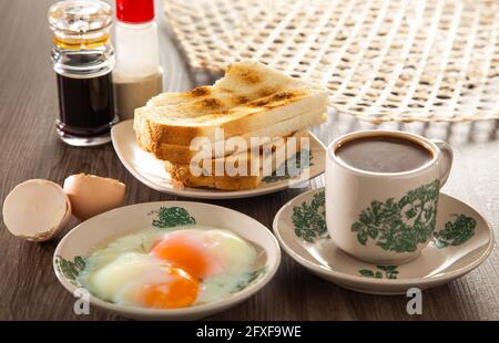 Gemeinsames orientalisches Frühstück in Malaysia, bestehend aus Kaffee, Nasi Lemak, Toastbrot und halbgekochtem Ei Stockfoto