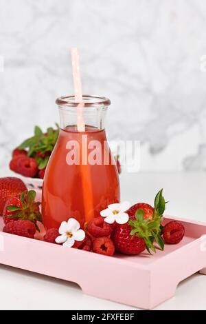 Rote Erdbeerfrucht Limonade im Glas, umgeben von Beeren Stockfoto