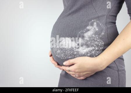 Eine Schwangere in Kleid hält die Hände auf dem Bauch mit einem Hologramm-Fond auf einem grauen Hintergrund. Nahaufnahme, Kopierbereich. Stockfoto
