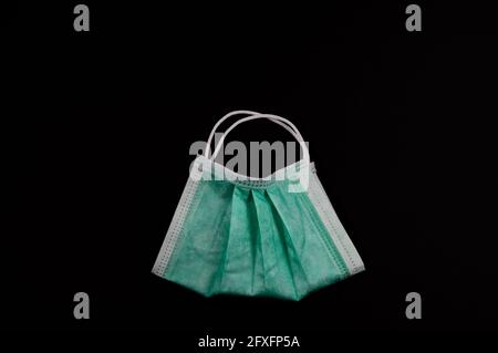 Gesichtsmaske in Form einer Tasche mit Griffen auf schwarzem Hintergrund. Das Konzept der Verwendung von persönlicher Schutzausrüstung beim Einkaufen während des Coronav Stockfoto