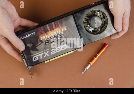 Grafikkarte Marke Gigabyte NVIDIA GeForce auf einem braunen Hintergrund. Der Mensch hält Dusty Computerkomponenten. Reparatur, Wartung von Computern Konzept. Kiew Stockfoto