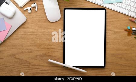 Draufsicht auf den Arbeitsbereich mit digitalem Tablet-PC: Beschneidungspfad, Zubehör und Schreibwaren auf Holztisch Stockfoto