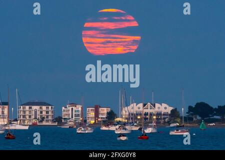 Poole, Dorset, Großbritannien. Mai 2021. Wetter in Großbritannien. Der Vollblumen-Supermond wird von Wolken verdeckt, als er aus der Reihe hinter Millionären bei Sandbanks bei Poole in Dorset aufsteigt. Bildnachweis: Graham Hunt/Alamy Live News Stockfoto