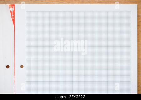 Notizbuch in Diagrammpapier. Echtes Papier auf einem Holzschreibtisch, ideal für einen Schul- oder Mathematikhintergrund, ein Konzept oder eine Vorlage Stockfoto