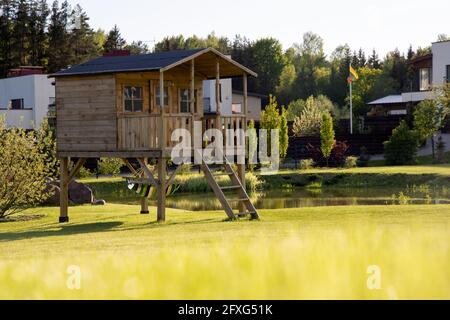 Kleines Kinderbaumhaus mit Hängematte im Garten an einem sonnigen Sommertag, warme und gemütliche Umgebung mit Rasen, Spielplatz Stockfoto