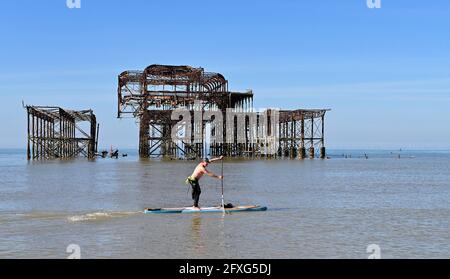 Brighton UK 27. Mai 2021 - EINE Paddelboarder passiert am West Pier in Brighton an einem schönen sonnigen Morgen mit einer heißeren, sonnigen Wettervorhersage, die über das Feiertagswochenende in Großbritannien eintreffen wird, wobei die Temperaturen im Südosten voraussichtlich über 20 Grad erreichen werden: Credit Simon Dack / Alamy Live News Stockfoto