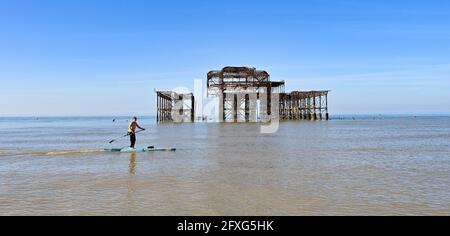 Brighton UK 27. Mai 2021 - EINE Paddelboarder passiert am West Pier in Brighton an einem schönen sonnigen Morgen mit einer heißeren, sonnigen Wettervorhersage, die über das Feiertagswochenende in Großbritannien eintreffen wird, wobei die Temperaturen im Südosten voraussichtlich über 20 Grad erreichen werden: Credit Simon Dack / Alamy Live News Stockfoto