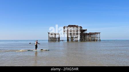Brighton UK 27. Mai 2021 - EINE Paddelboarder passiert am West Pier in Brighton an einem schönen sonnigen Morgen mit einer heißeren, sonnigen Wettervorhersage, die über das Feiertagswochenende in Großbritannien eintreffen wird, wobei die Temperaturen im Südosten voraussichtlich über 20 Grad erreichen werden: Credit Simon Dack / Alamy Live News Stockfoto