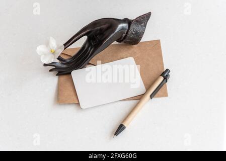 Halter mit Blume Visitenkarte Umschlag und Stift auf Tisch Stockfoto