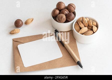 Visitenkarte und Stift auf Umschlag von exotischen Nüssen auf Tabelle Stockfoto