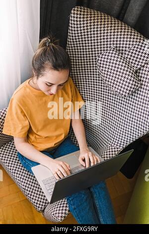 Frau im bequemen Sessel, die am Laptop arbeitet Stockfoto