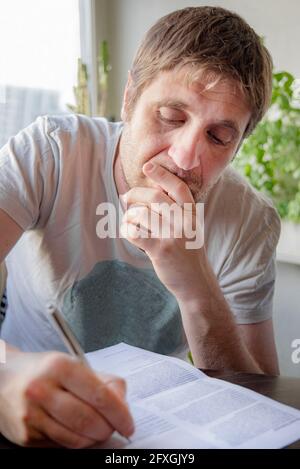 Kaukasischer blonder Mann in seinen 30ern Unterzeichnung Vertrag Dokument Stockfoto