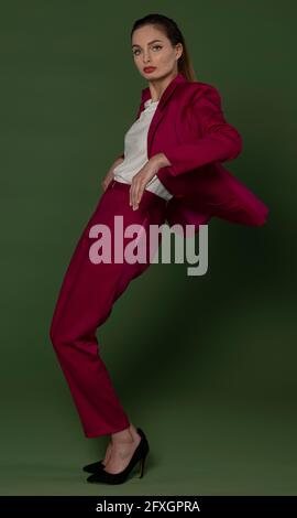 Gorgeus junges Mädchen in fuchsia elegantes Kleid posiert in Mode Stil auf grünem Hintergrund Stockfoto