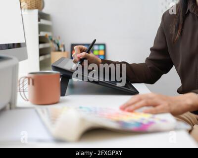 Nahaufnahme der weiblichen Grafikdesigner-Hände, mit denen gearbeitet wird Zeichentablett und Farbfeld Stockfoto