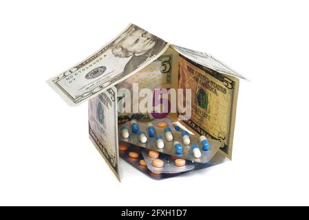 Haufen von Pillen in Blisterpackungen in einem Haus gemacht Von Dollar-Banknoten isoliert auf weißem Hintergrund Stockfoto