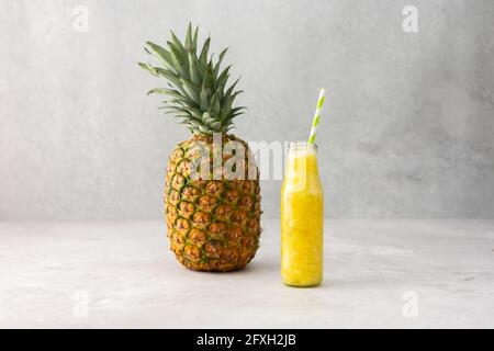 Ganze reife köstliche Ananasfrucht und Ananas Smoothie in einem Glas mit einem Stroh, kopieren Raum Stockfoto