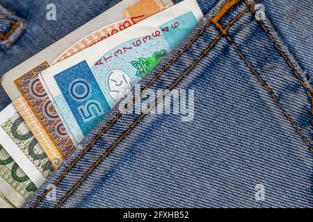 Viele polnische Scheine ragen aus der Gesäßtasche der Denim-Hose. Foto aufgenommen unter künstlichem, weichem Licht Stockfoto