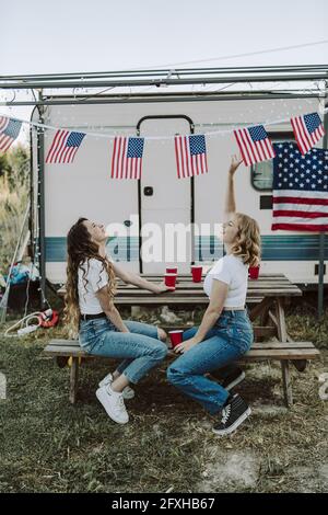 Eine schöne Aufnahme von zwei spanischen Frauen, die ihre Zeit genießen Auf dem Hintergrund der US-Flaggen-US-Unabhängigkeitstag Stockfoto