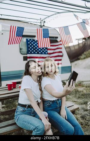 Eine schöne Aufnahme von zwei spanischen Frauen, die ein Selfie machen Auf dem Hintergrund der US-Flaggen - Tag der US-Unabhängigkeit Stockfoto