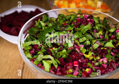 Frische, gehackte Rote-Bete-Blätter in einer Glasschüssel angeordnet. Foto aufgenommen unter künstlichem, weichem Licht. Stockfoto