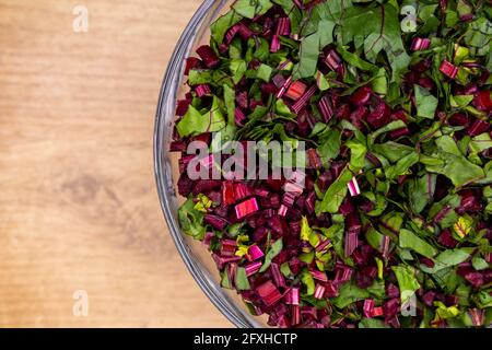 Frische, gehackte Rote-Bete-Blätter in einer Glasschüssel angeordnet. Foto aufgenommen unter künstlichem, weichem Licht. Stockfoto