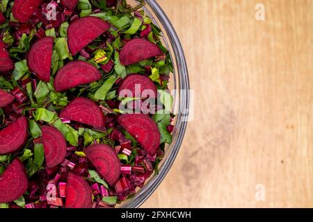 Frische, geschnittene Blätter und Rote Beete in einer Glasschüssel angeordnet. Foto aufgenommen unter künstlichem, weichem Licht. Stockfoto