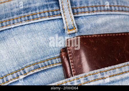 Die Ledertasche ragt aus der Gesäßtasche der Denim-Hose. Foto aufgenommen unter künstlichem, weichem Licht Stockfoto