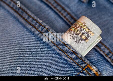 Viele polnische 200-pln-Banknoten ragen aus der Gesäßtasche der Denim-Hose. Foto aufgenommen unter künstlichem, weichem Licht Stockfoto