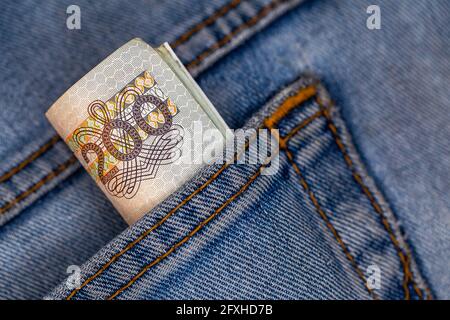 Viele polnische 200-pln-Banknoten ragen aus der Gesäßtasche der Denim-Hose. Foto aufgenommen unter künstlichem, weichem Licht Stockfoto