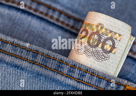 Viele polnische 200-pln-Banknoten ragen aus der Gesäßtasche der Denim-Hose. Foto aufgenommen unter künstlichem, weichem Licht Stockfoto