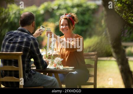 Glückliches Paar, das sich am sonnigen Gartentisch festklebte Stockfoto