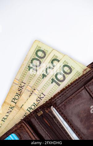 Viele polnische Banknoten ragen aus einer braunen Ledertasche. Foto aufgenommen unter künstlichem, weichem Licht, Objekt isoliert auf weißem Hintergrund Stockfoto