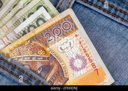 Viele polnische Scheine ragen aus der Gesäßtasche der Denim-Hose. Foto aufgenommen unter künstlichem, weichem Licht Stockfoto