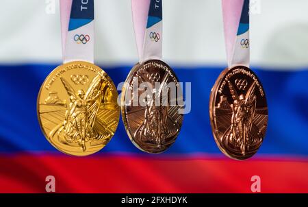 25. April 2021 Tokio, Japan. Gold-, Silber- und Bronzemedaillen der XXXII. Olympischen Sommerspiele 2020 in Tokio auf dem Hintergrund der russischen Flagge. Stockfoto