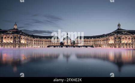 FRANKREICH. GIRONDE( 33), BORDEAUX, DER PLACE DE LA BOURSE MIT DEM WASSERSPIEGEL IN LANGER EXPOSITION GEGENÜBER DER BLAUEN STUNDE (ARCHITEKTEN SPIEGEL WASSER, MICHEL CORAJO Stockfoto