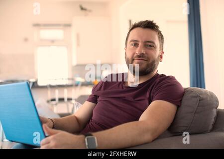 Portrait selbstbewusster Mann, der von zu Hause aus am Laptop arbeitet Stockfoto