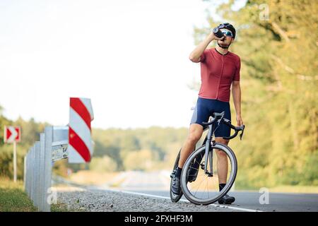 Mann im aktiven Ohr trinkt frisches Wasser aus der Flasche Stockfoto
