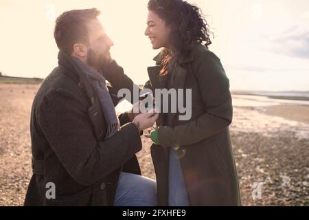 Freund mit Ehering schlägt Freundin am Winterstrand vor Stockfoto