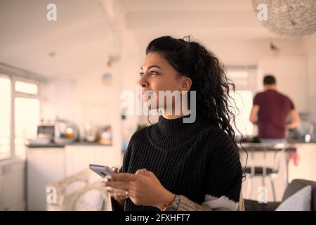 Lächelnde, schöne Frau, die zu Hause Smartphone benutzt Stockfoto