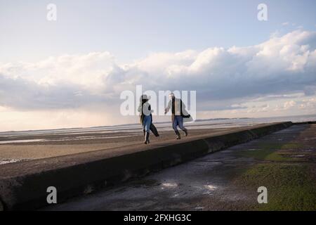 Pärchen, die auf dem Meeresstrand-Steg laufen Stockfoto